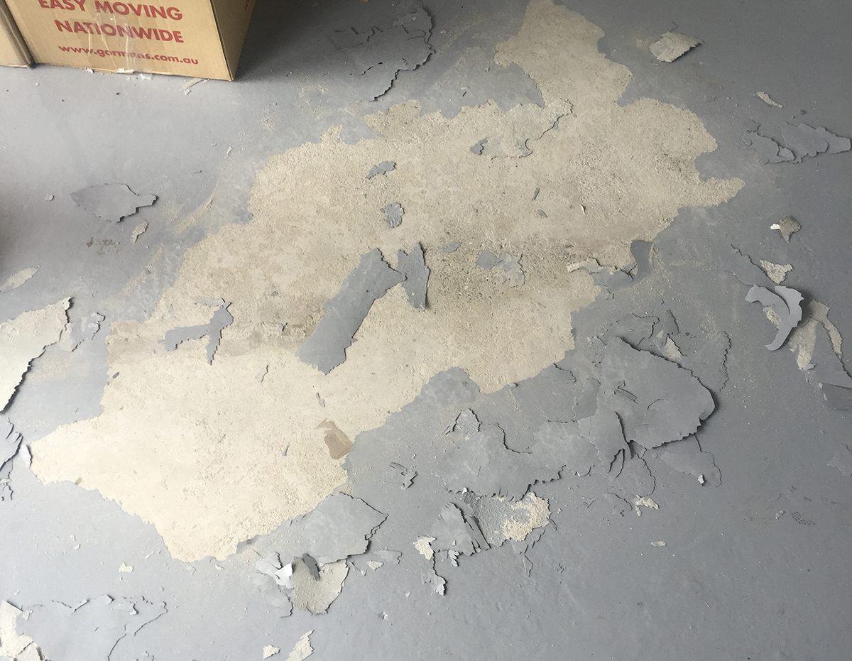 An existing floor coating that looks weak and flaky.