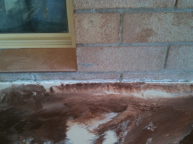 Bleeding of epoxy resin under tape next to bricks in a home.