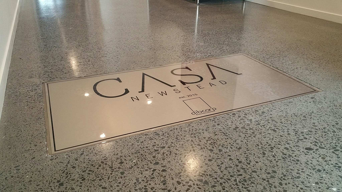 A clear epoxy resin used to encapsulate a logo in the entrance of an apartment building.