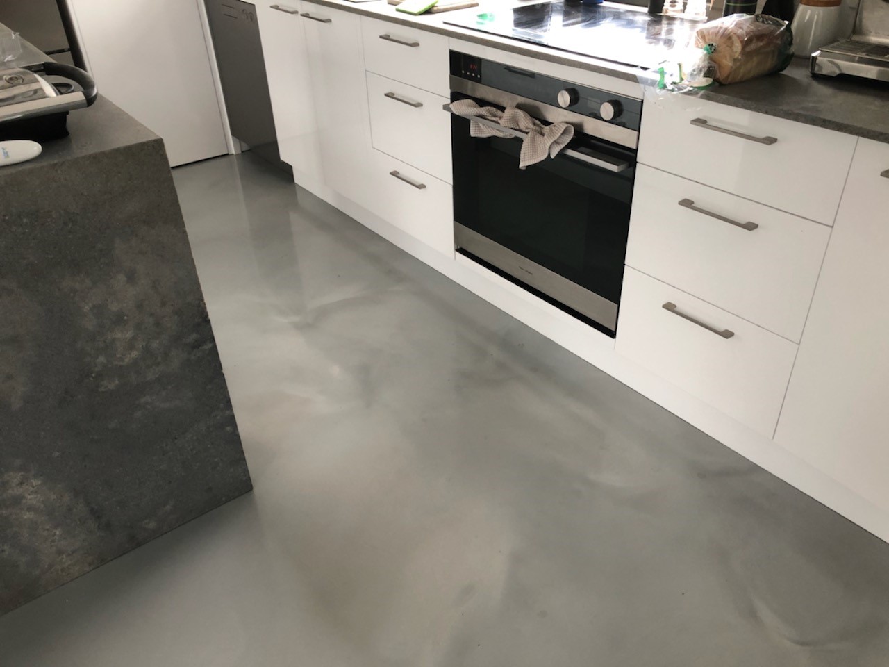 A grey metallic decorative floor in a small apartment kitchen.