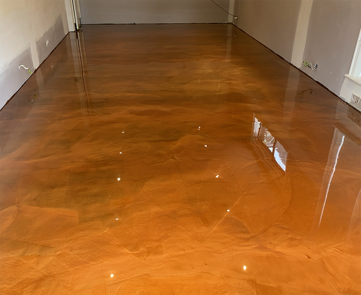 A deep copper metallic epoxy floor in an empty retail space.