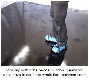 A black epoxy floor with dull patches from being sanded with a pole sander.