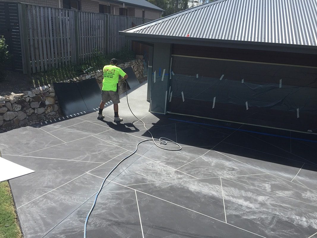 An applicator spraying concrete resurfacing products onto a driveway.
