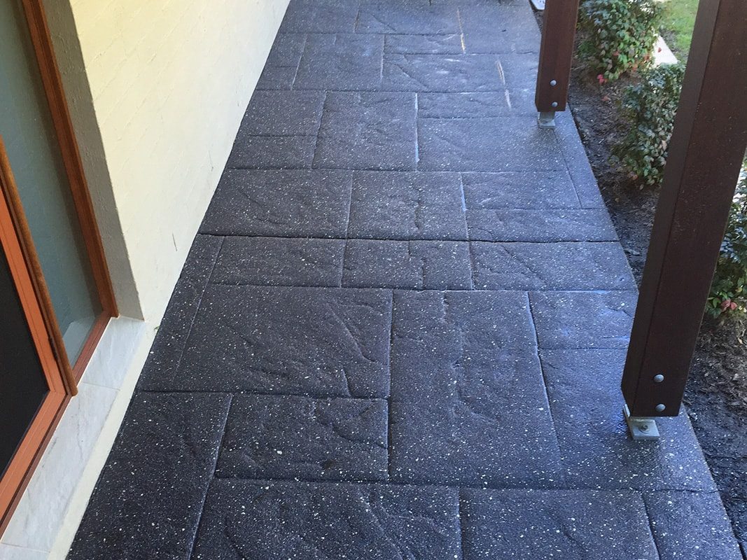 A walkway along the side of a house that has been resurfaced with a stamped concrete finish.