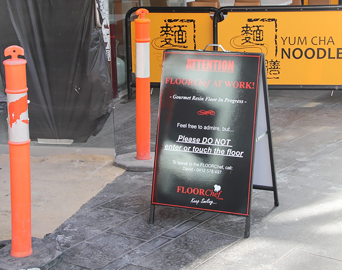 Sign and barricades protecting an epoxy flooring installation.