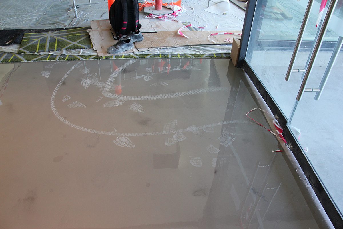 Footprints and tyre marks on a new epoxy flooring installation.