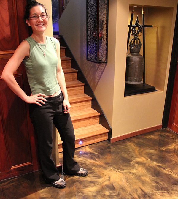 A smiling floor owner standing on their new epoxy floor after installation.