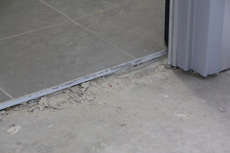 A side angle picture of tiles showing the total thickness of the floor before removal.