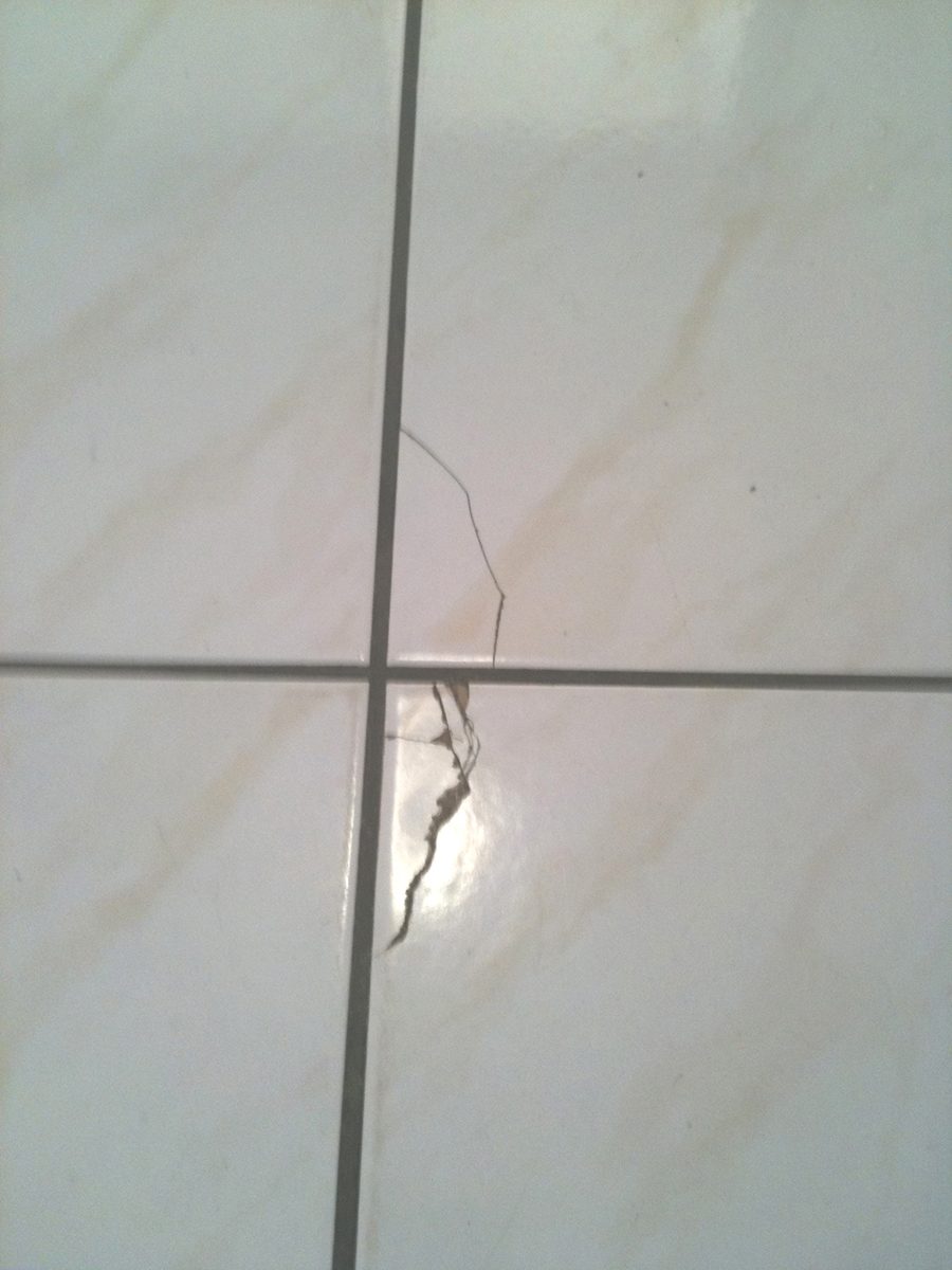 Cracks on the edge of tiles in a kitchen from dropping heavy items.