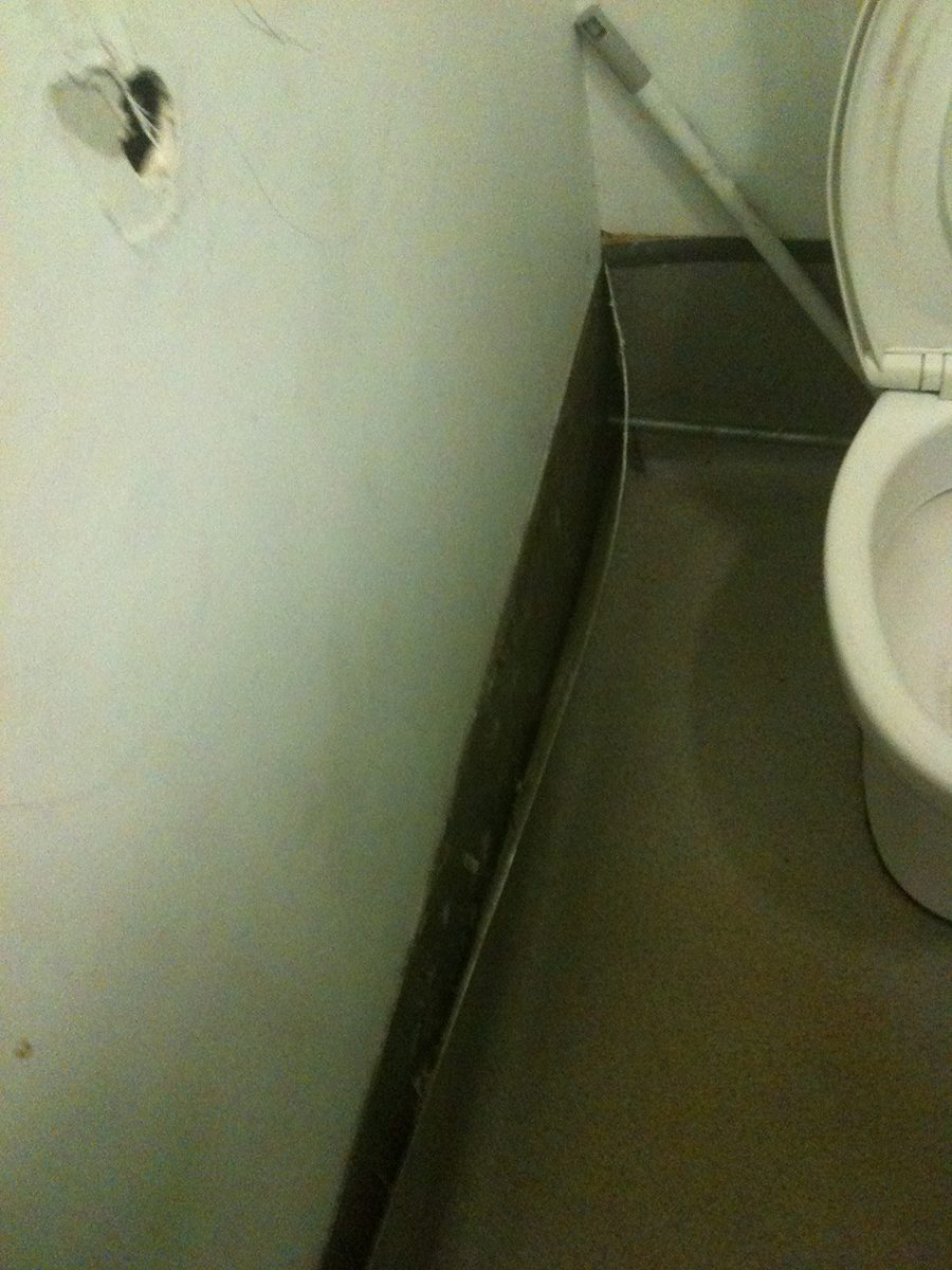 Vinyl peeling off the sides of a public toilet stall.