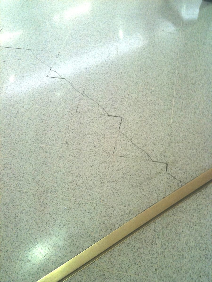 A large crack forming across a tiled floor due to subfloor movement.