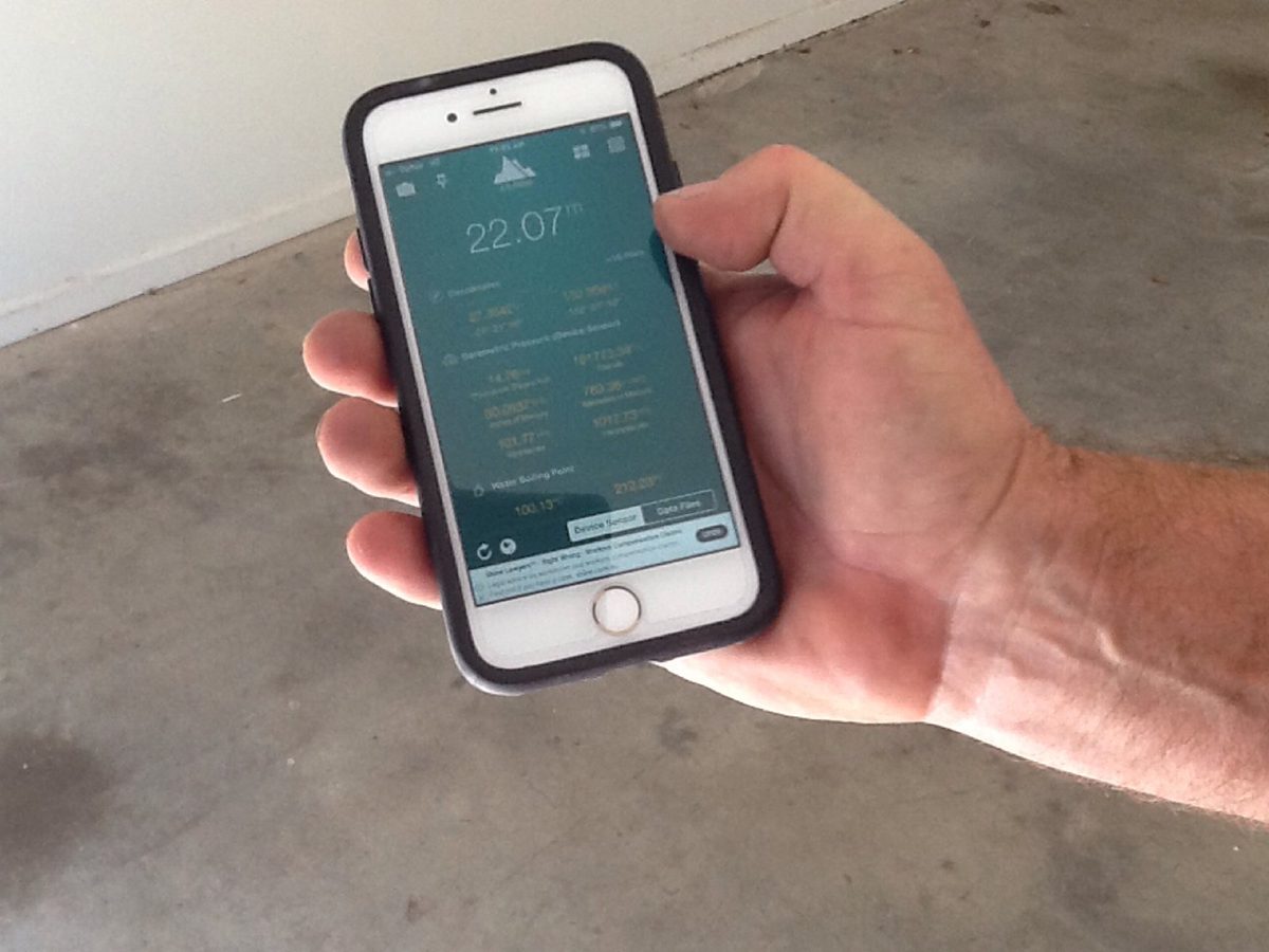 An installer using a mobile phone to check atmospheric conditions before beginning epoxy flooring application.