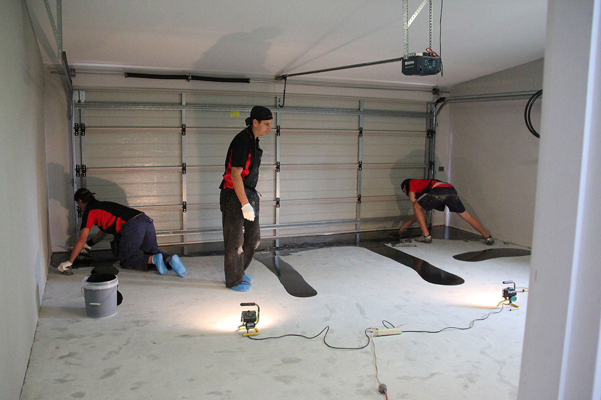 An epoxy flooring installation team working together on a garage floor.