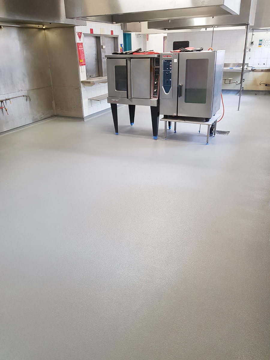 A piece of equipment sits on top of a newly applied Jaxxon floor coating in a commercial kitchen.