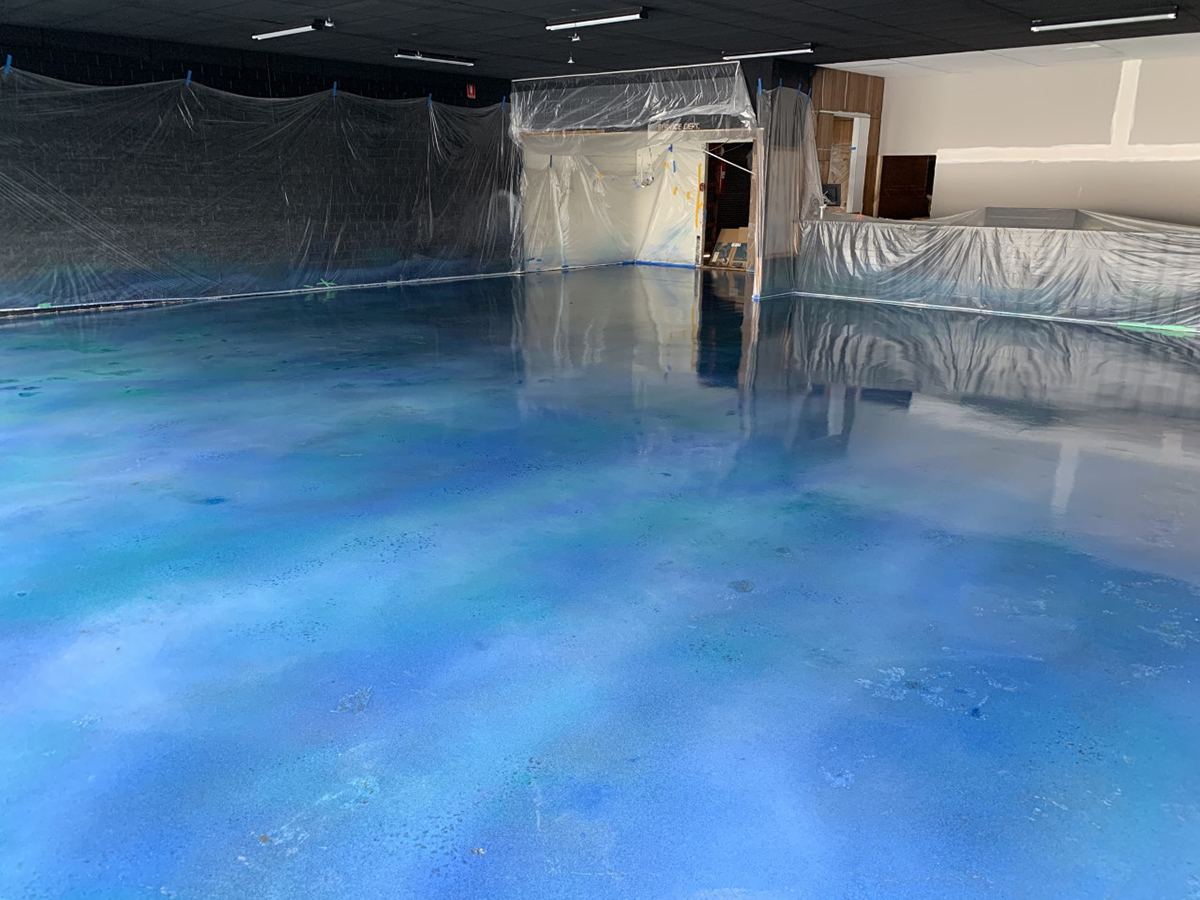 An empty store waiting to be fitted out after having an ocean-like blue floor installed using Artepoxy Liquid Crystal.
