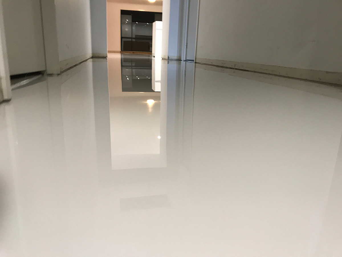 A low-angle shot looking down the hallway of a home showing the beautiful, high-gloss finish of a clear epoxy resin.