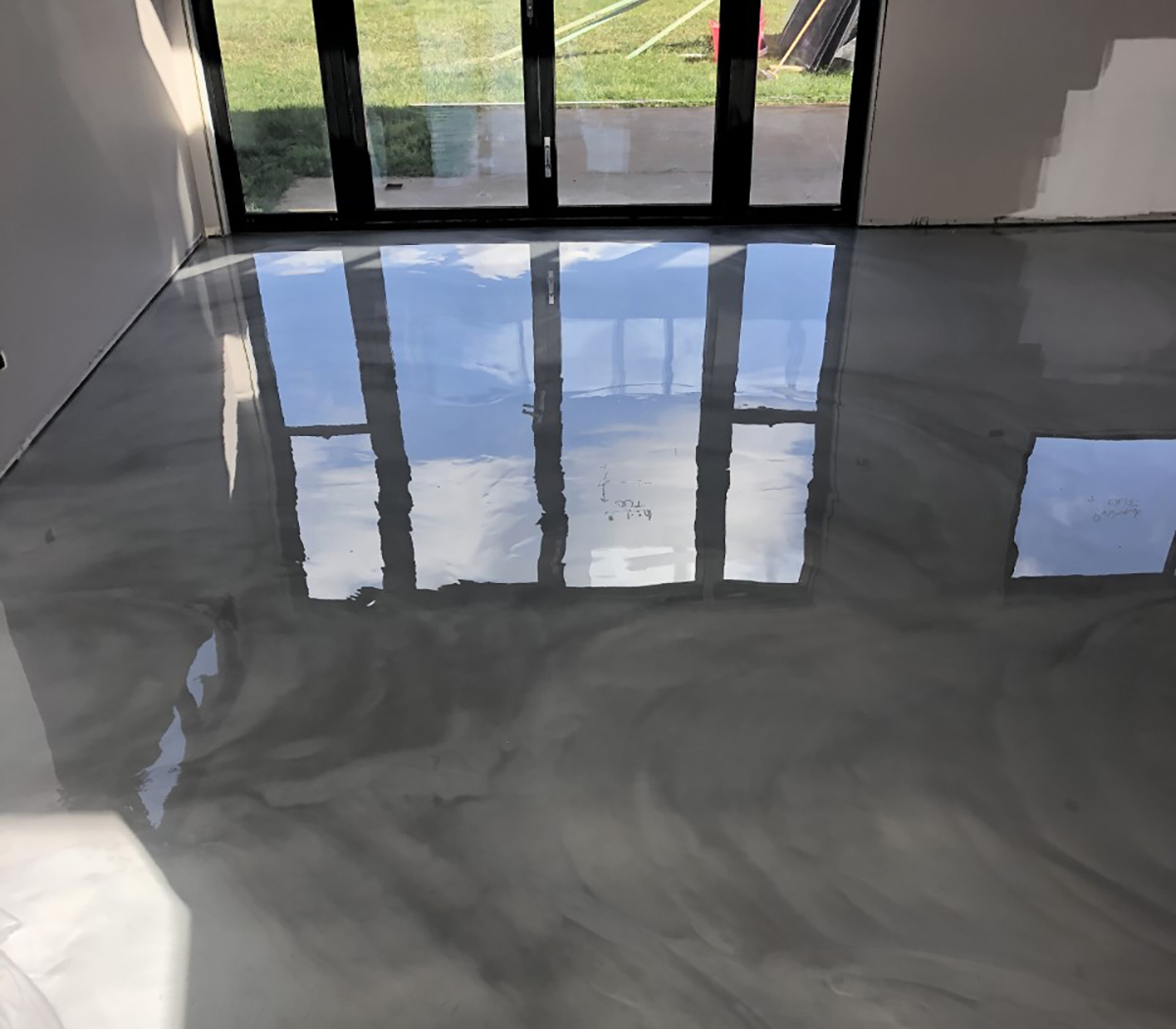 A swirling grey metallic floor next to large windows showing off the high-end finish of Artepoxy Liquid Crystal.