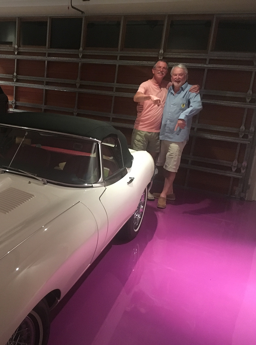 Owners of vintage cars hugging and smiling on top of their new deep pink Artepoxy Liquid Crystal garage floor.