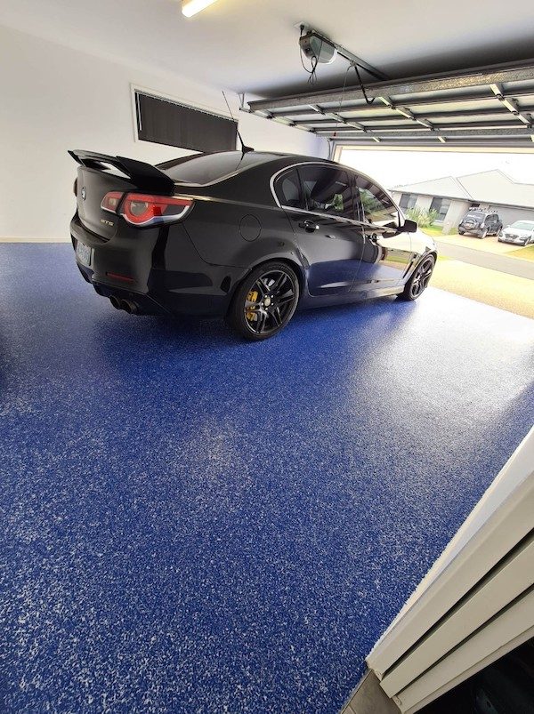 A modern car sitting on top of a blue finish created with garage floor coatings.