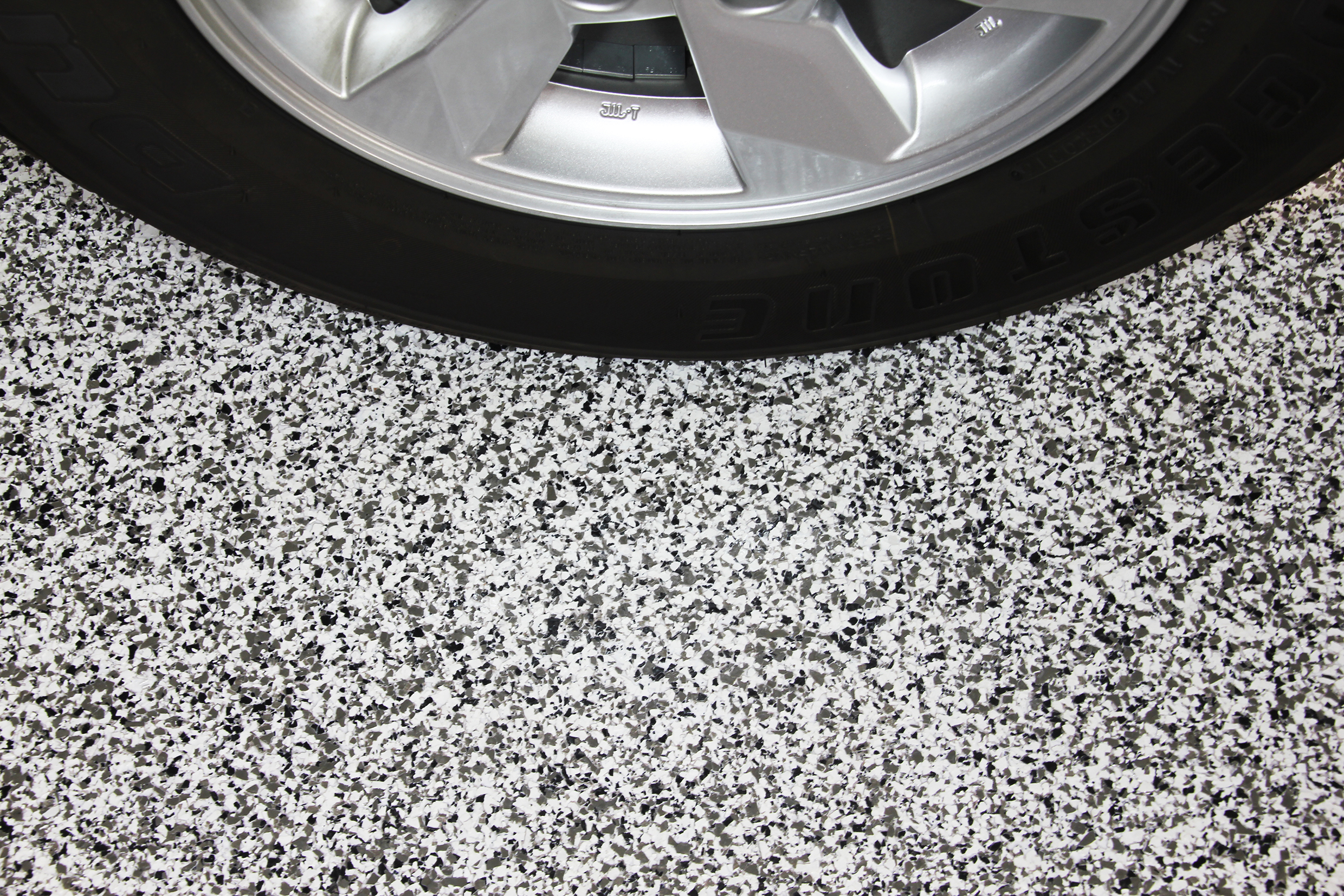 A car tyre sitting on top of a flake floor that used high-quality garage floor coatings.