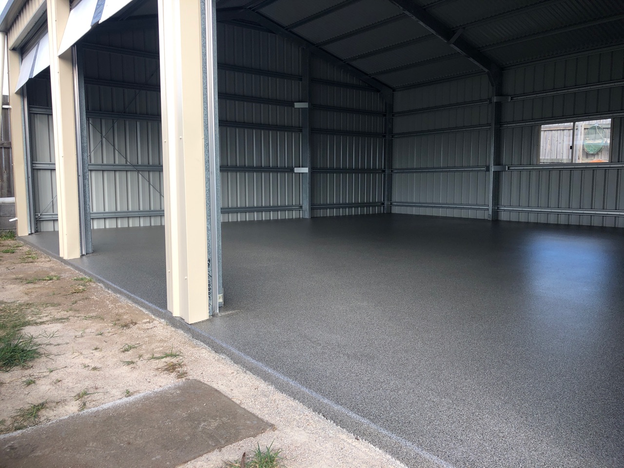 A large, 3-door residential garage with freshly applied garage floor coatings visible.