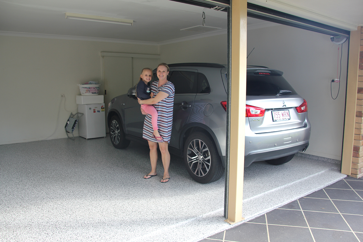 A homeowner and her daughter smiling while standing on top of their new garage floor coatings.