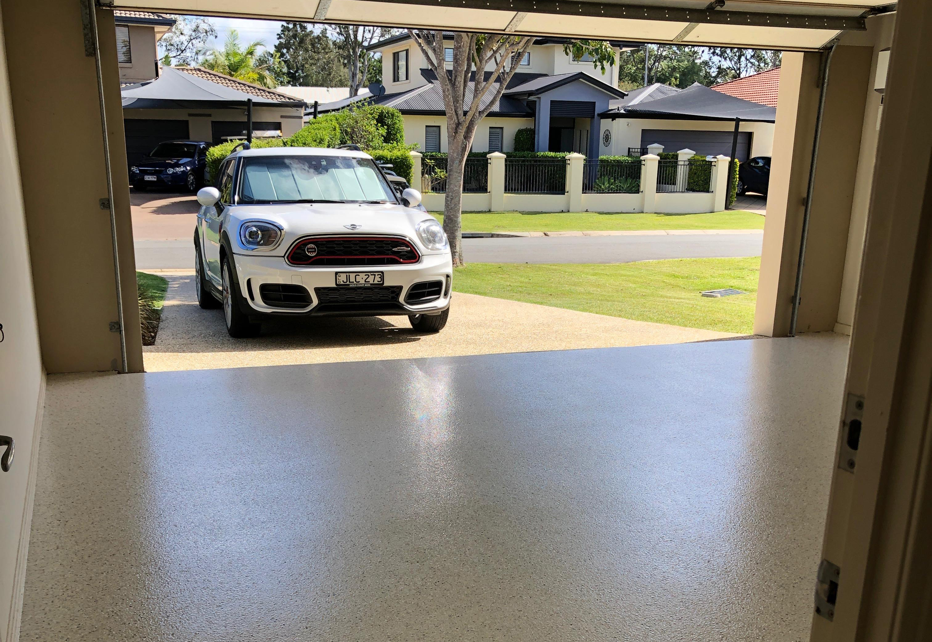 A photo taken from inside a residential garage showing a car preparing to drive onto the new garage floor coatings.