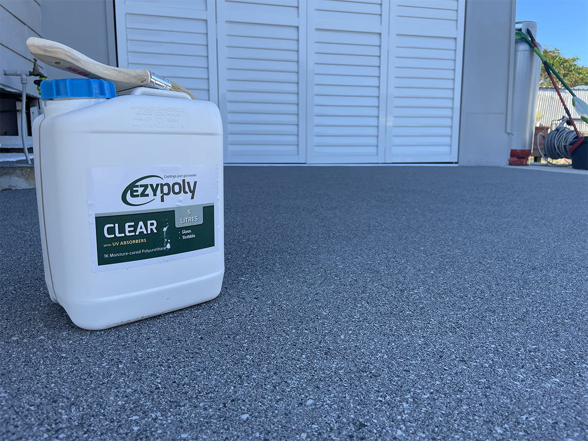 A drum of Ezypoly one-pack, solvent-free polyurethane topcoat sitting on top of a new epoxy flake floor in a garage.