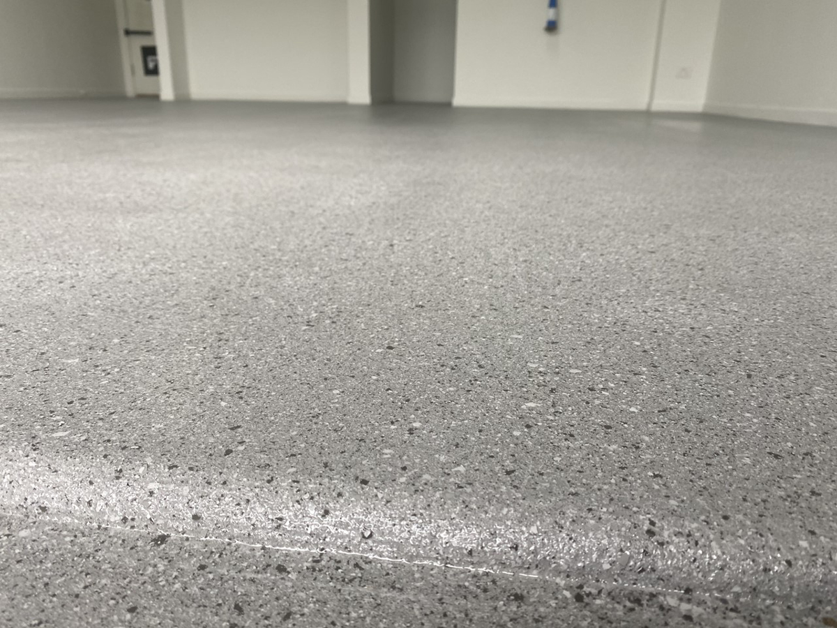 A low-angle shot of an epoxy flake floor from the front of a residential garage showing the strong, even finish of the topcoat.