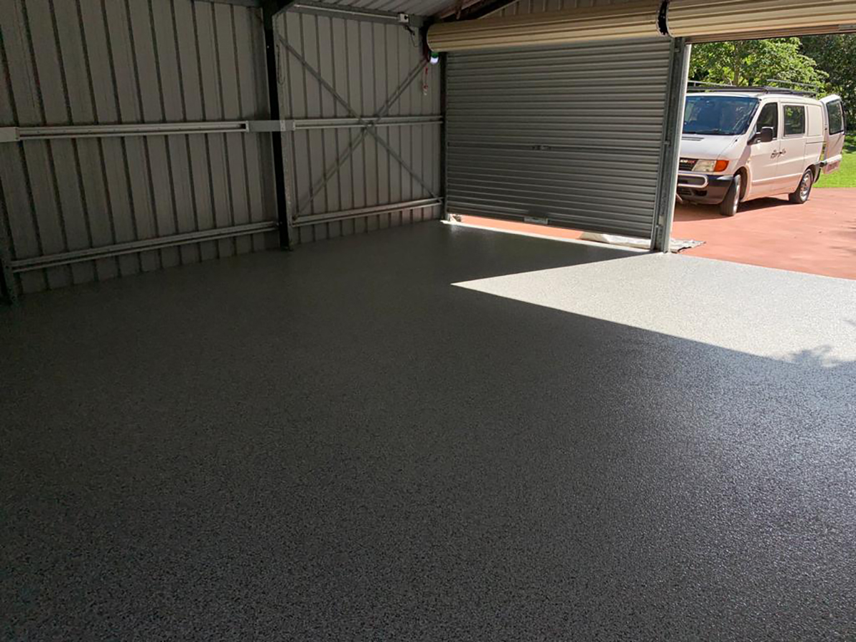 A photo taken from the back of a large residential garage with a new epoxy flake floor installed.