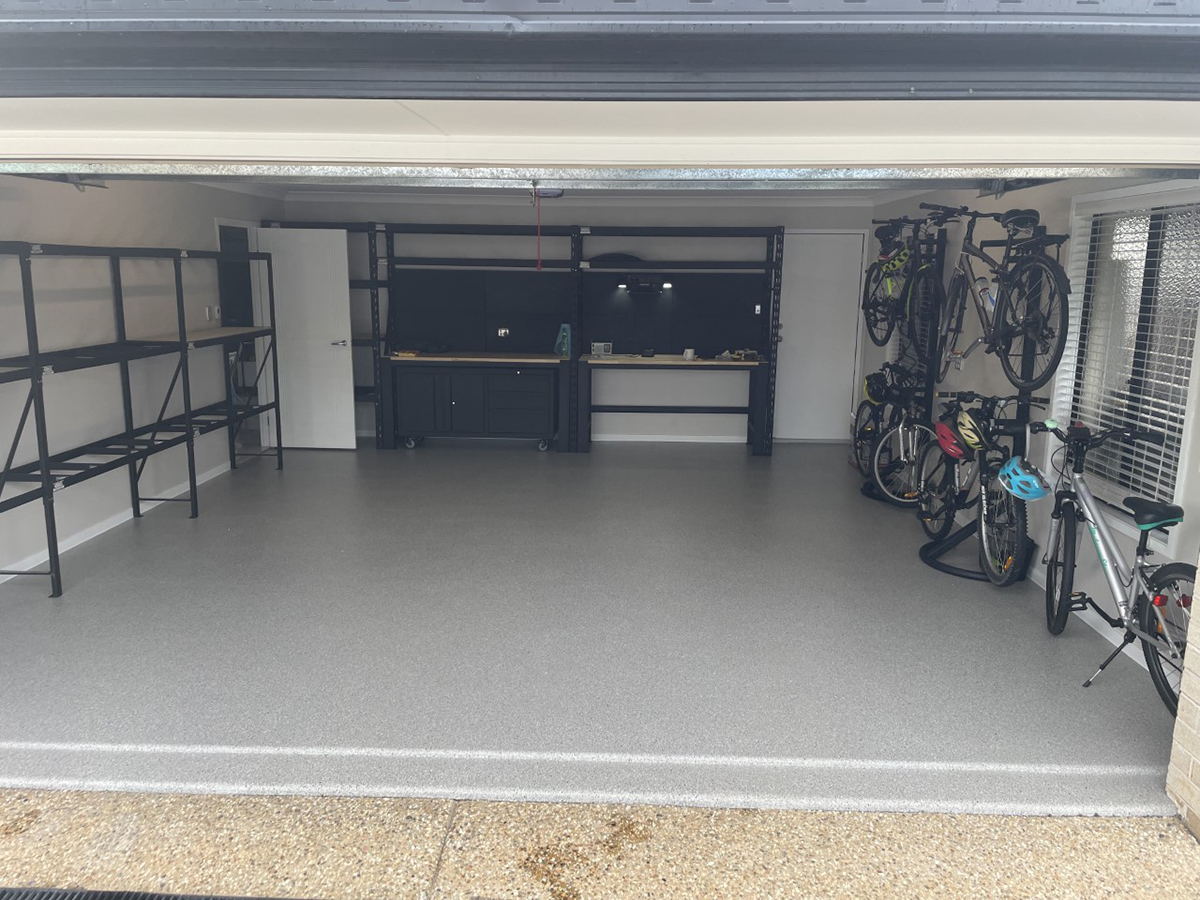 A residential garage with shelving and bicycle racks and a beautiful new epoxy flake floor.