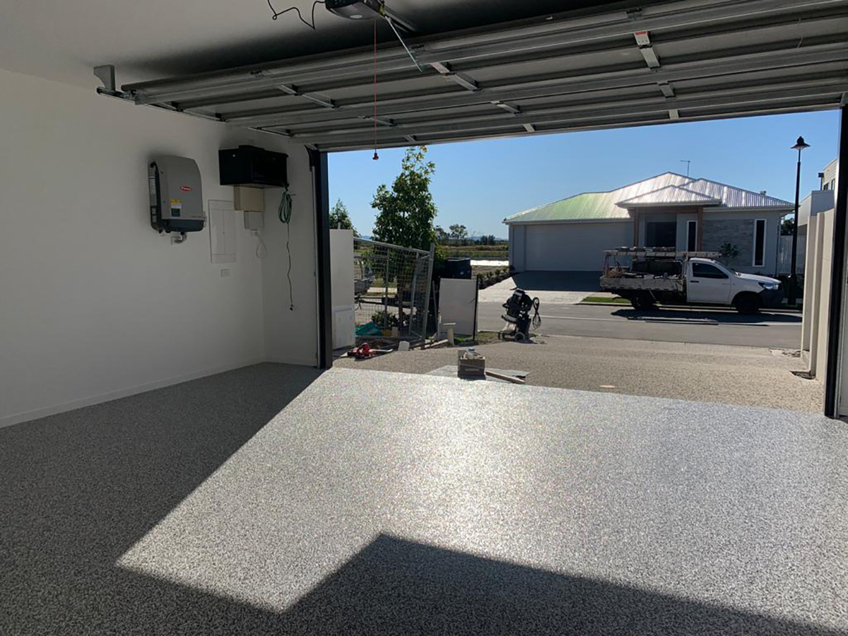 A photo taken from the back of a residential garage showing the strong, consistent finish of the epoxy flake floor.