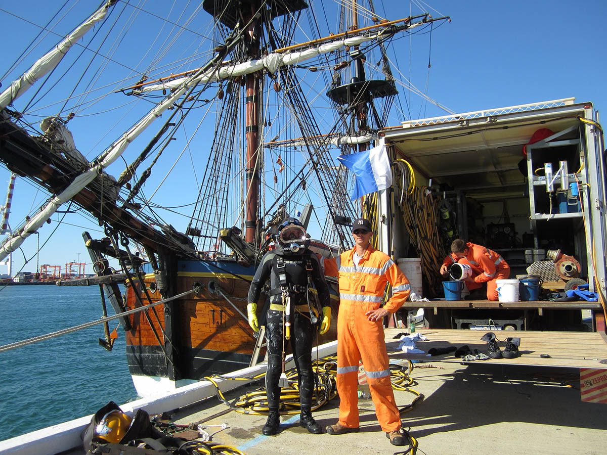 A diver standing on the pier with his support crew before conducting the repairs.