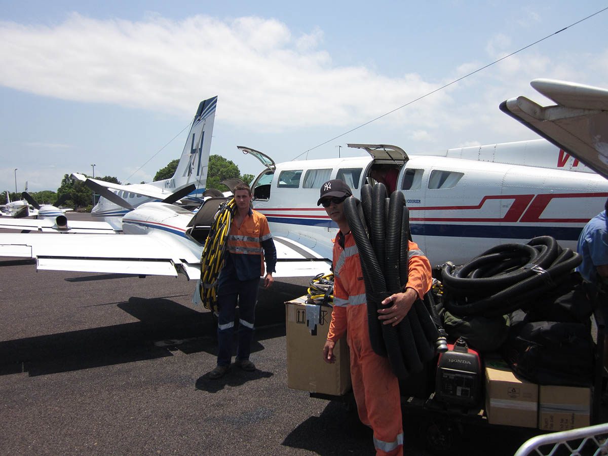 Divers standing outside of a plane on the airport tarmac before flying to the remote island.