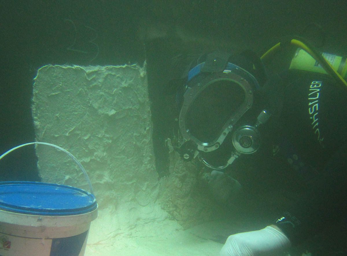 A diver pauses application to take a photo of the repair in the tank.
