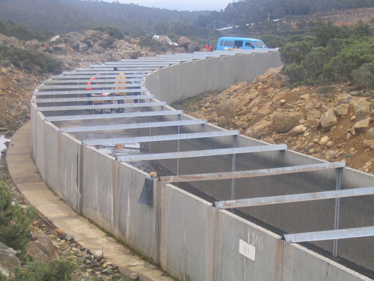 A photo of the empty flume from above with the installation crew inside applying the sealant system.