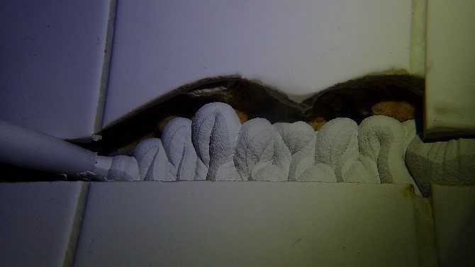 A close up of the expansion joint being filled with fresh sealant from the nozzle of the caulking gun.