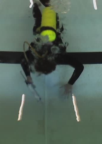 A diver using a caulking gun to apply Scubapoxy 5335 into a swimming pool expansion joint while underwater.