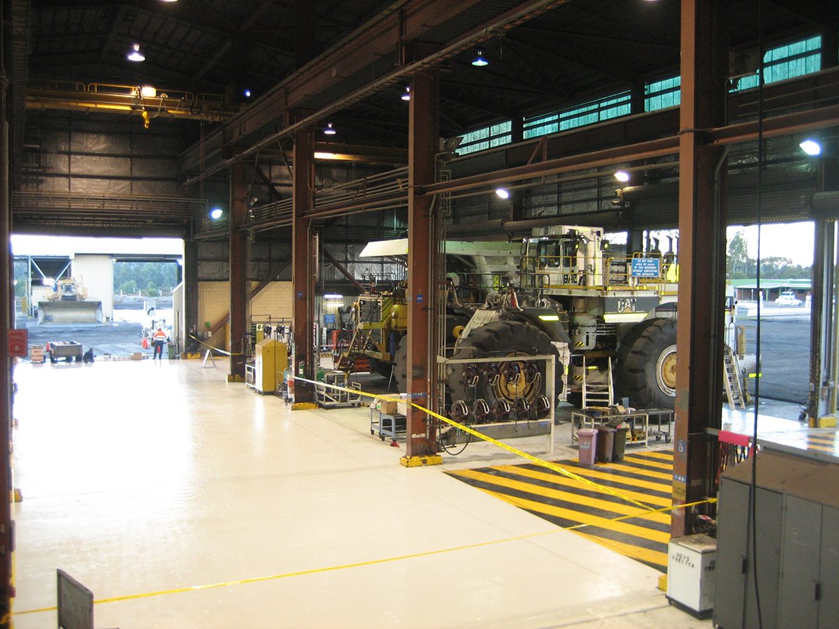 A photo taken at the completion of the project showing large mining vehicles parked in the workshop undergoing maintenance.