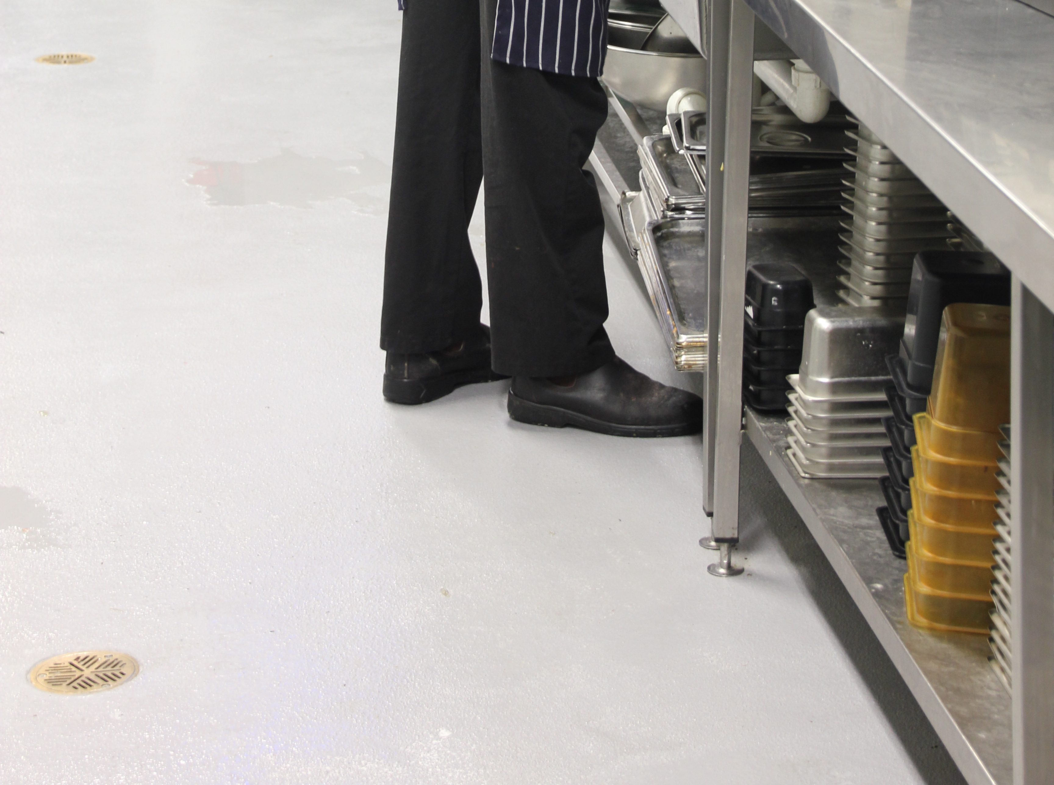 A close up of a chef working on the new non-slip epoxy floor that is wet from spills and splashes.