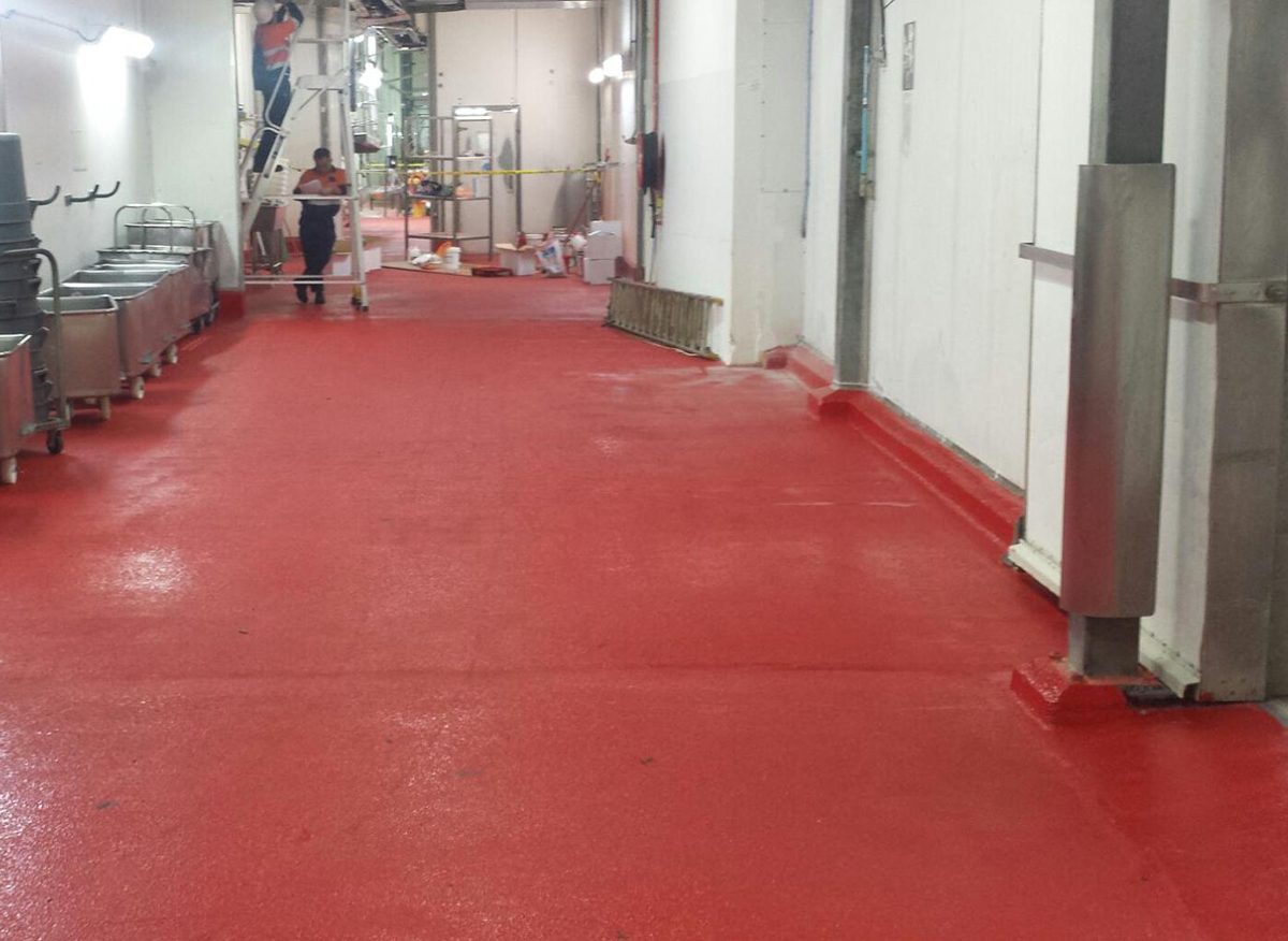 A photo taken at the completion of the project showing the vibrant signal red non-slip epoxy floor being used by workers in the abattoir.