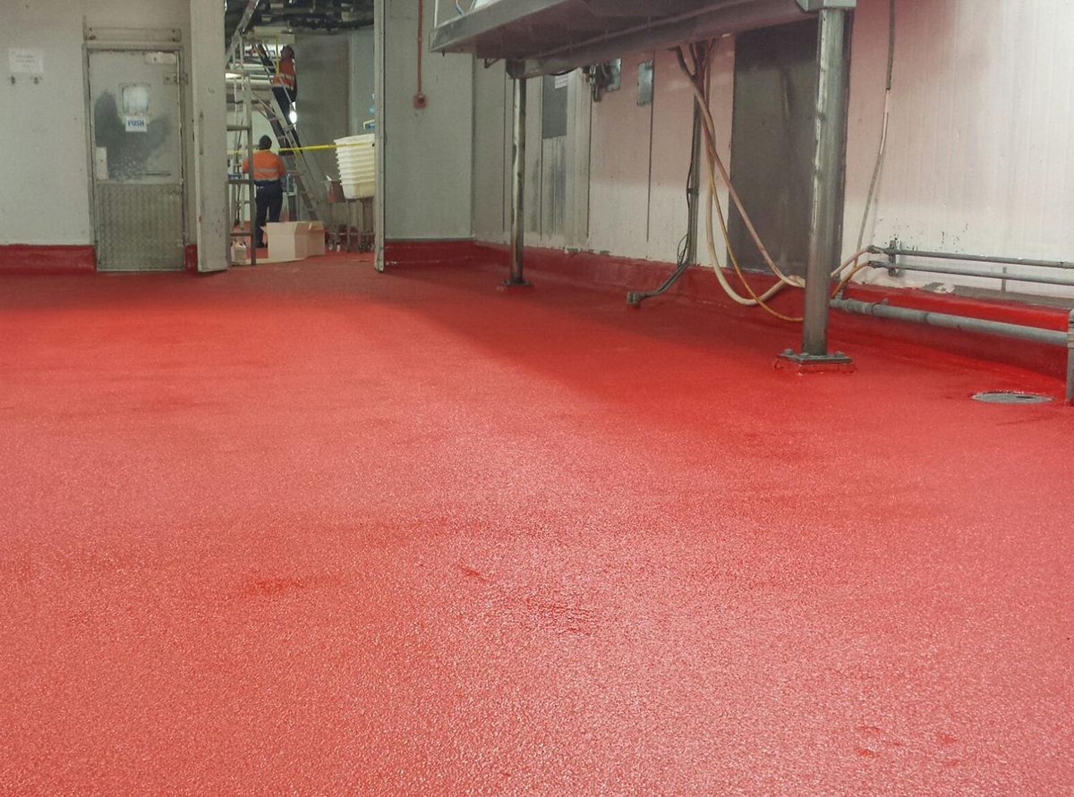 A low angle shot of the vibrant signal red non-slip epoxy floor showing the aggressive non-slip texture required in the abattoir.