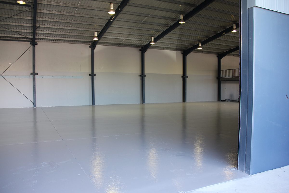A view of the empty warehouse from the open front door showing the new protective epoxy floor covering the large area.