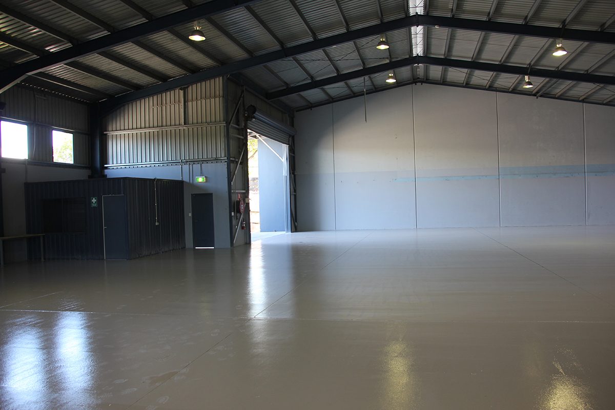A view from inside the empty warehouse looking back towards the entrance with the new protective epoxy floor in the foreground.