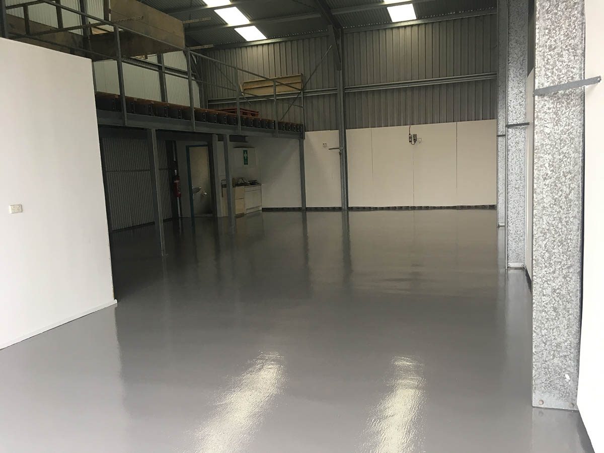 The front of the warehouse with door open, showing the new protective epoxy floor and the brightening effect of the light grey finish.