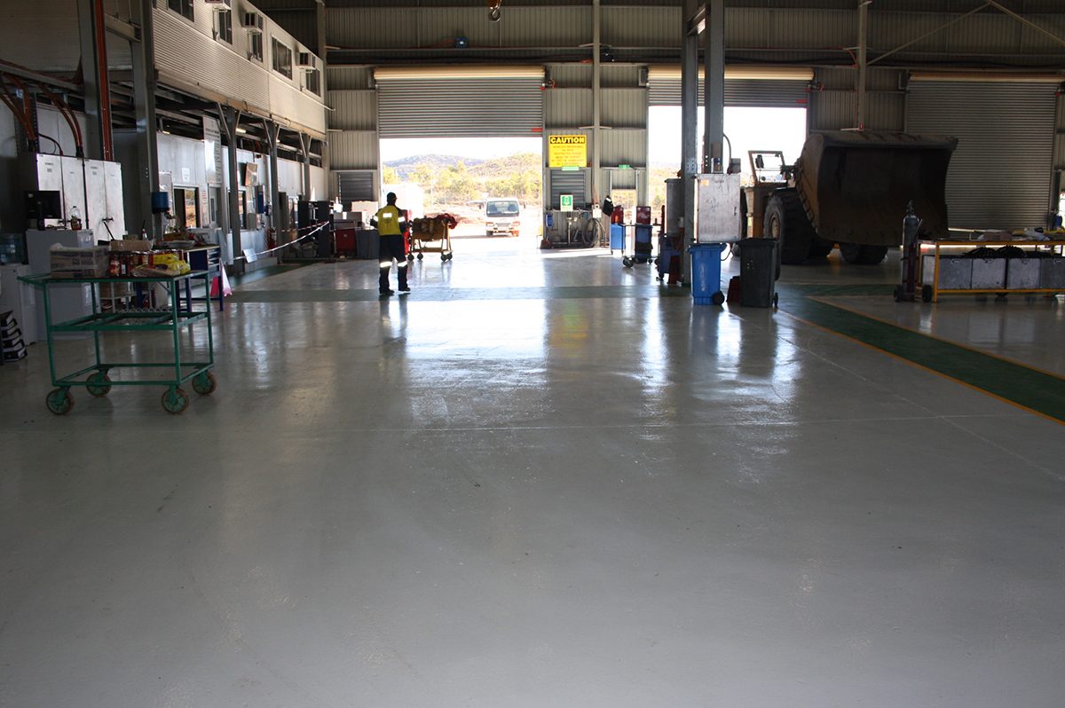 A photo taken at floor level showing workers, bins and trolleys on the new protective epoxy floor near the offices.